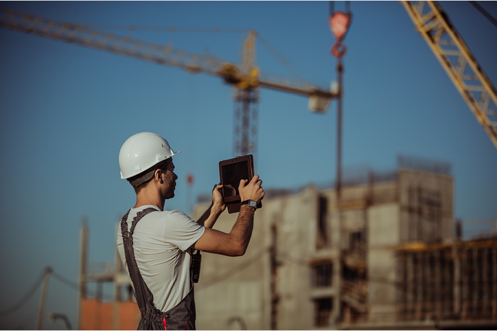 homme tenant un iPad sur un chantier et prenant une photo